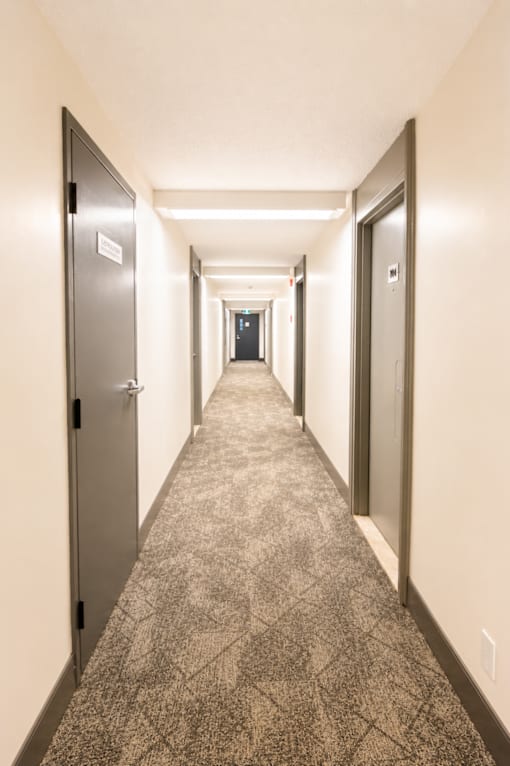 A long hallway with doors on both sides and a carpeted floor.