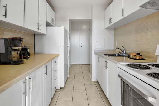 A kitchen with white cabinets and a stove top oven.