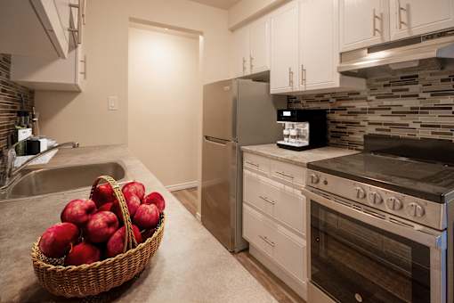 A kitchen with a refrigerator, oven, and sink.