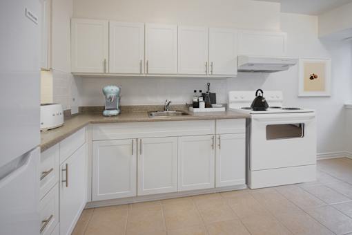 A white kitchen with a sink, stove, and oven.