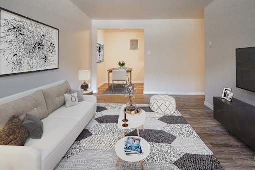 A living room with a white couch, a coffee table, and a large abstract painting on the wall.