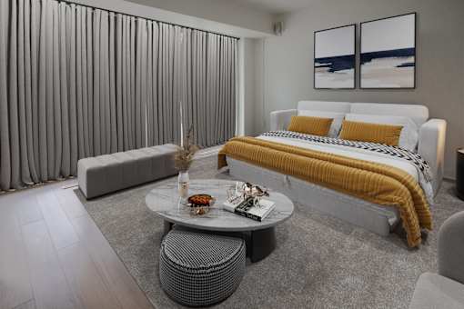 A modern bedroom with a large bed and a grey sofa.
