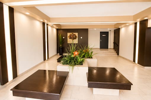 A long hallway with a bench and a flower arrangement in the middle.