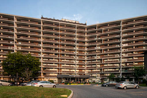 A large apartment complex with a parking lot in front.