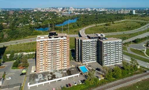 Two large buildings are situated next to a pool and a road.