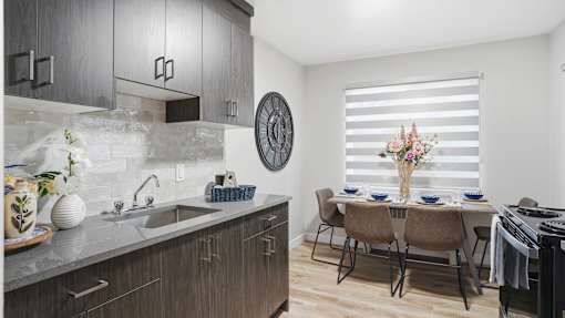 A modern kitchen with a dining table set for two.