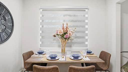 A dining table set with blue and white plates and a vase of flowers.