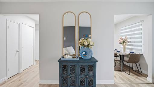 A blue cabinet with a mirror and flowers on top.