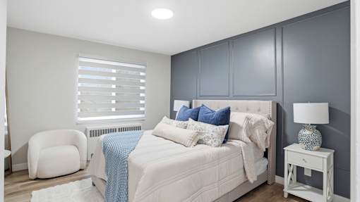 A bedroom with a white bed and a white chair.