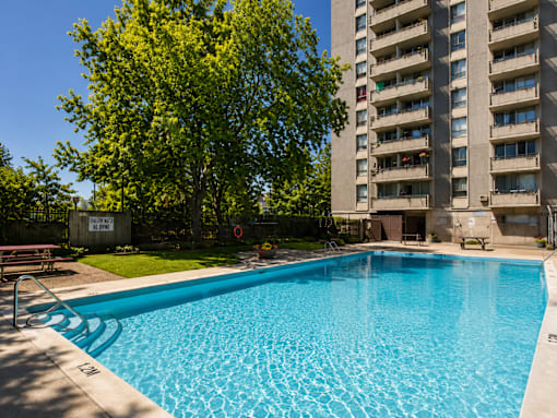 A blue swimming pool in front of a tall building.