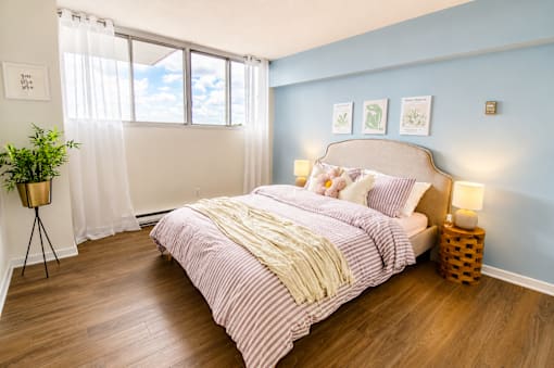 A bedroom with a bed, a lamp, and a potted plant.