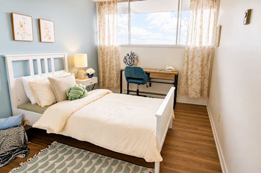 A bedroom with a bed, desk, and chair.