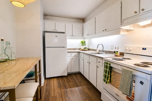 A kitchen with white appliances and wooden floors.