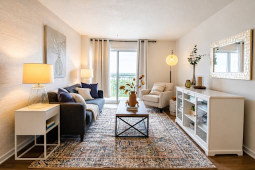 A living room with a grey couch, a white side table, a black and white coffee table, and a white cabinet.