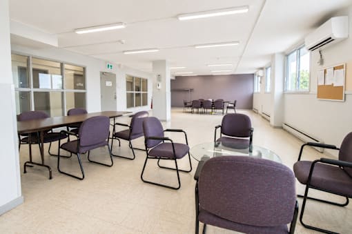 A conference room with purple chairs and a glass table.
