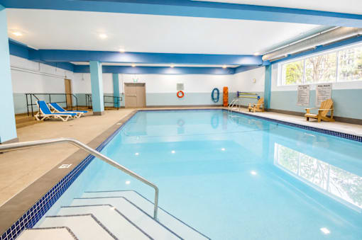 A large indoor swimming pool with a blue tiled edge and a metal ladder.