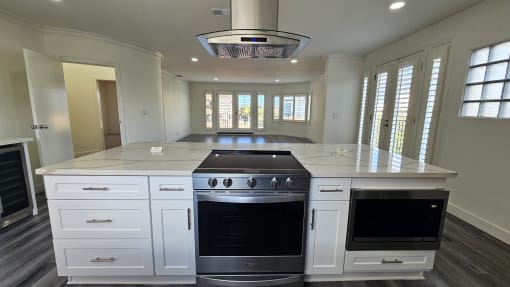 a large white kitchen with an island and stainless steel appliances