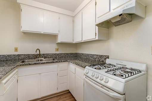 a kitchen with white appliances and granite counter tops and white cabinets