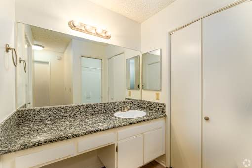 a bathroom with a granite counter top and a large mirror