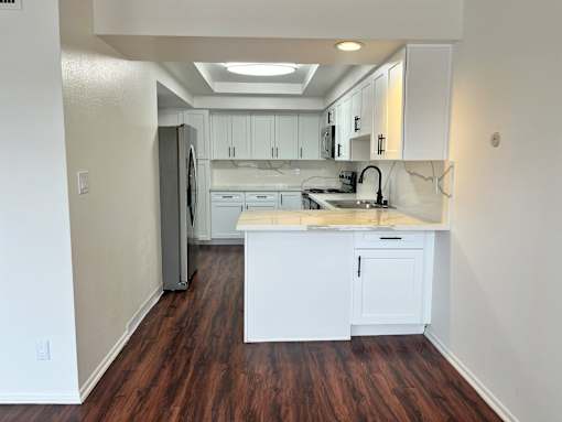 Dresden kitchen with white cabinets and a wooden floor.
