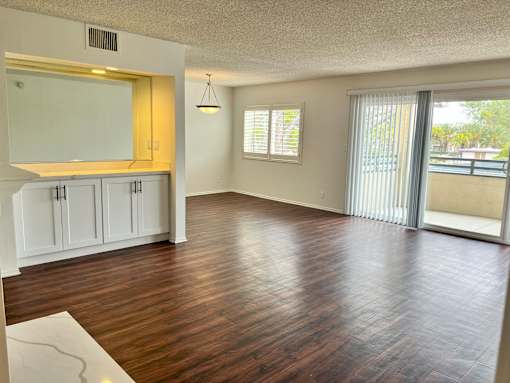 A spacious living room with wood flooring and white cabinetry.
