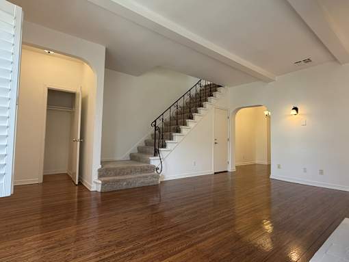 A spacious room with a staircase and wooden flooring.