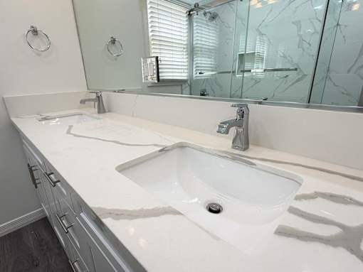 A white sink with a silver faucet is in the middle of a marble countertop.