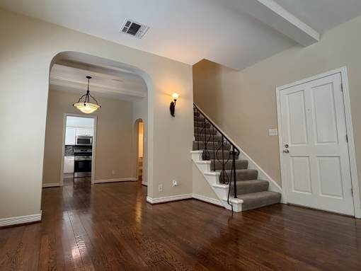 A spacious room with a staircase leading to the second floor.