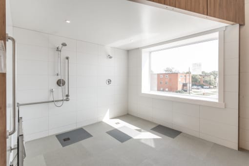 a bathroom with a large window and a shower with a grab rail