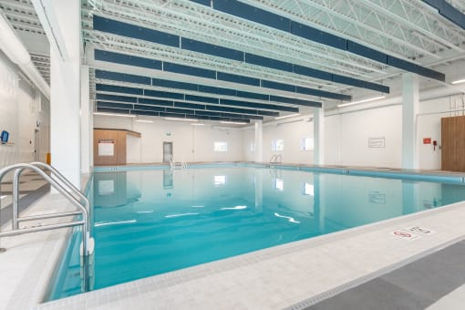 a large indoor swimming pool with white walls and white tiles