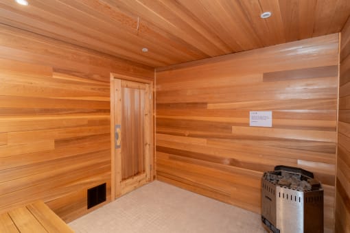 a wooden sauna with a door and a trash can