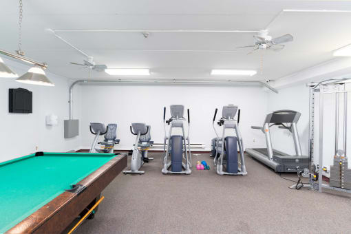 a gym with a pool table and exercise machines