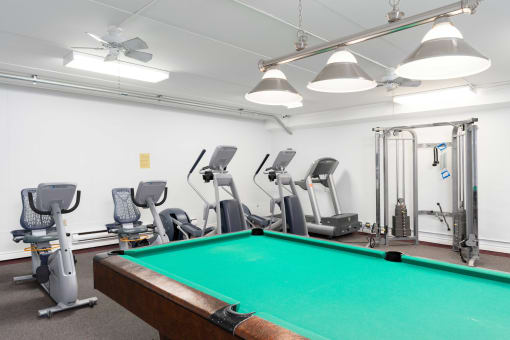 a room with a pool table and gym equipment