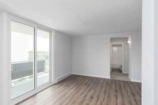 an empty living room with a sliding glass door and hardwood floors
