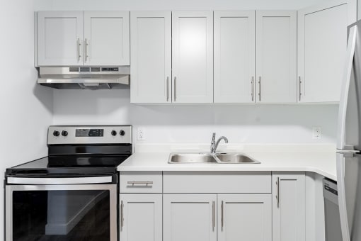 a white kitchen with white cabinets and black and white appliances