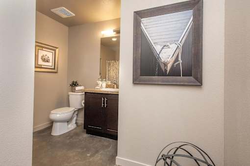 A bathroom with a toilet, sink, and a painting on the wall.
