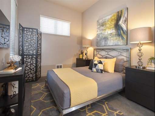 A bedroom with a bed, nightstand, and lamp.