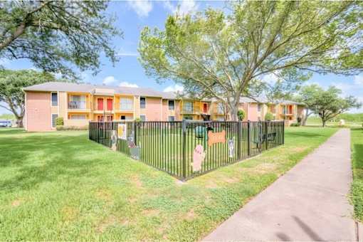 Apartment complex with a black fence and green grass.