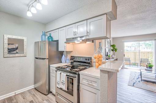 A kitchen with a stainless steel refrigerator, oven, and cabinets.