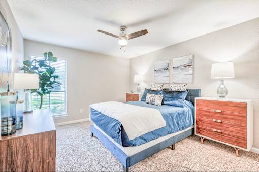 A bedroom with a bed, nightstand, and a ceiling fan.