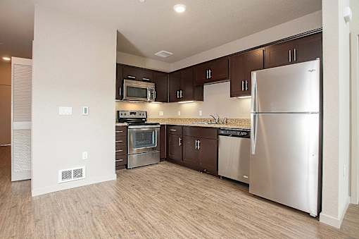 A kitchen with a refrigerator, oven, and microwave.