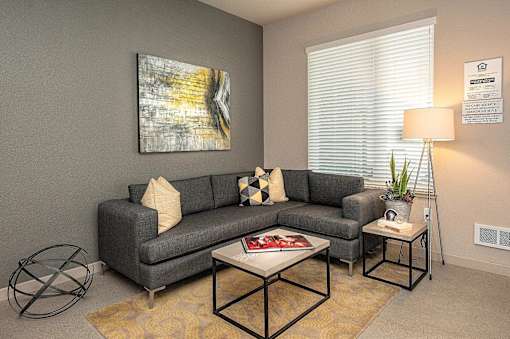 A living room with a grey couch, a coffee table, and a painting on the wall.