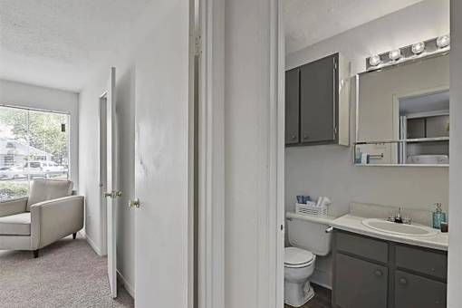 A bathroom with a toilet, sink, and mirror.