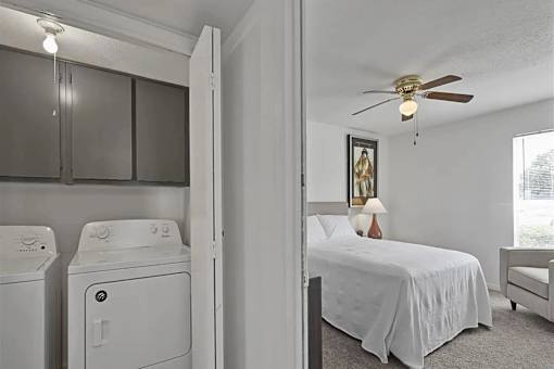 A bedroom with a bed, a chair, and a washing machine.