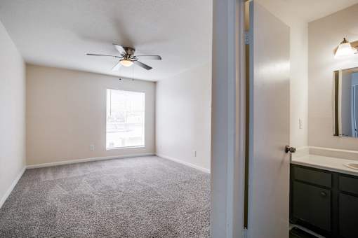 A room with a ceiling fan and carpeted floor.