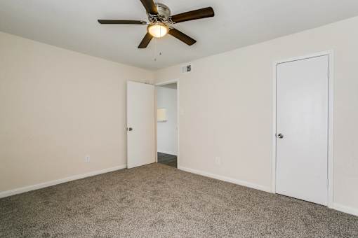 A room with a ceiling fan and carpeted floor.
