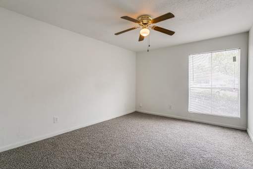 A room with a ceiling fan and carpeted floor.