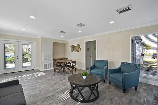 A living room with a grey sofa, a wooden table, and two chairs.