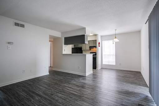 A spacious living room with a kitchenette in the background.