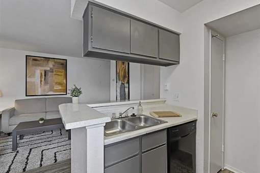 A modern kitchen with a white countertop and grey cabinets.